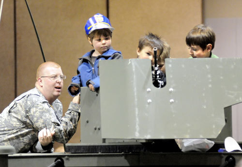 Alaska Army National Guard Staff Sergeant Michael Manson helps kids climb on a HumVee and handle a M249 Saw gun mounted to the roof during the Southeast Alaska Outdoor Safety Expo sponsored by Juneau Rotary in the Centennial Hall on Saturday.  Juneau EmpireMay 24, 2009 